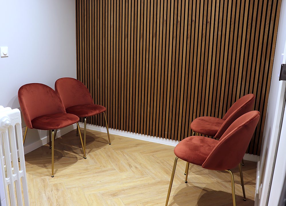 Salle d'attente partagée, mur en tasseaux de bois et fauteuils