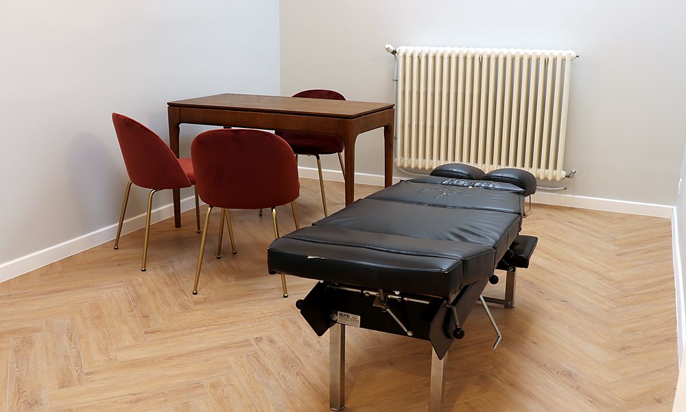 Salle de face vue depuis la porte, table de chiropraxie et bureau